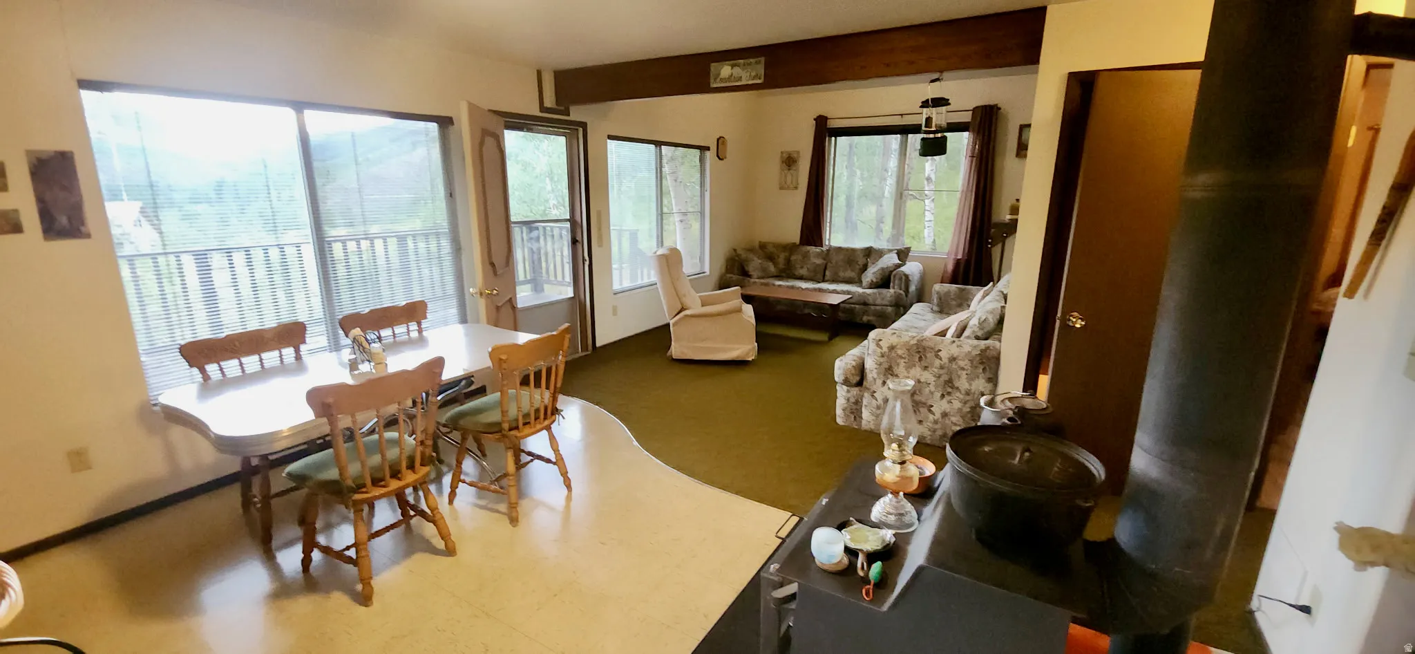 Open-concept living area featuring a wood-burning stove and exposed ceiling beam