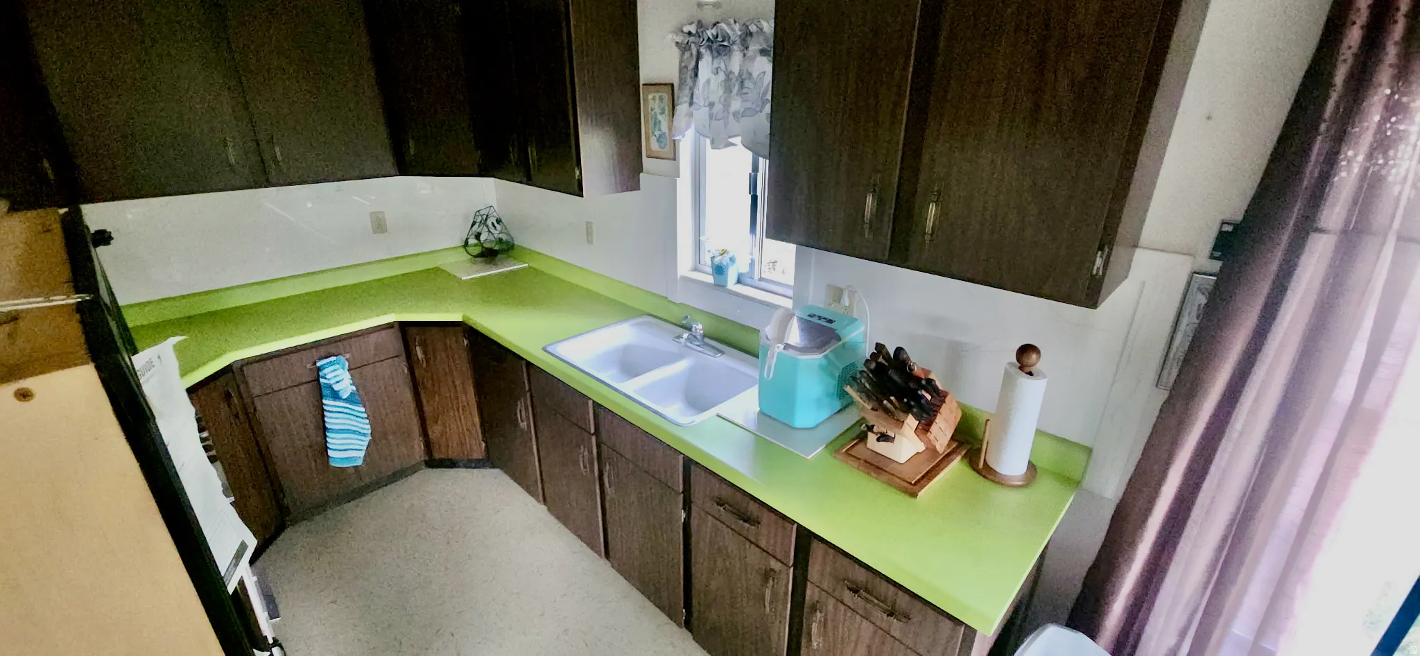 Kitchen featuring wood-finish cabinetry, a double basin sink, and ample countertop space