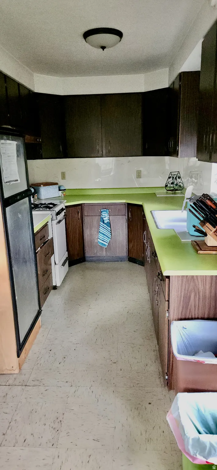 Galley kitchen with wood-finish cabinetry, light green countertops, and a built-in sink