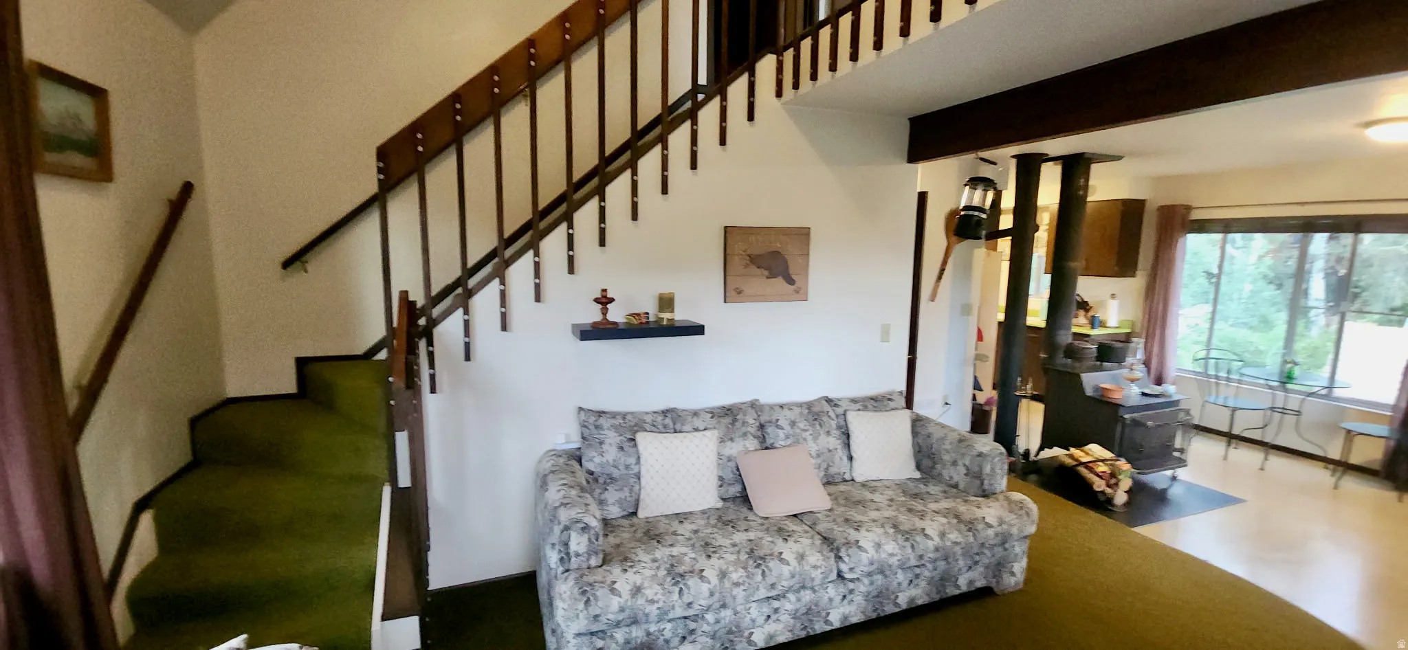 Wood-finish stairway with railing, wood-burning stove with hearth, and large windows