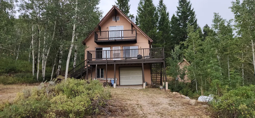 A-frame cabin with clapboard, two expansive decks, an integrated garage, and a lush, tree-lined setting