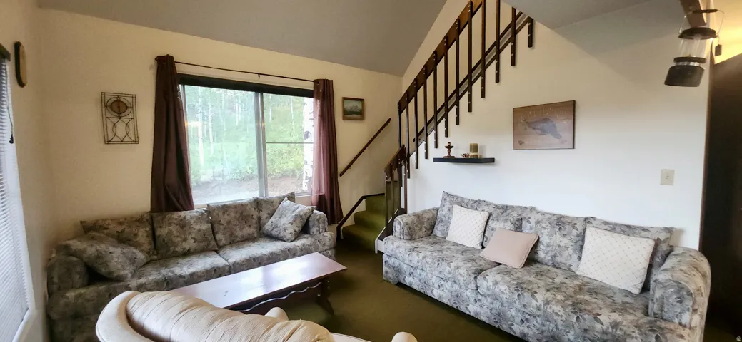 Vaulted ceiling with an open staircase featuring wood railings