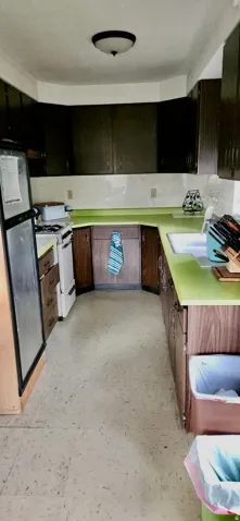 Galley kitchen with wood-finish cabinetry, light green countertops, and a built-in sink