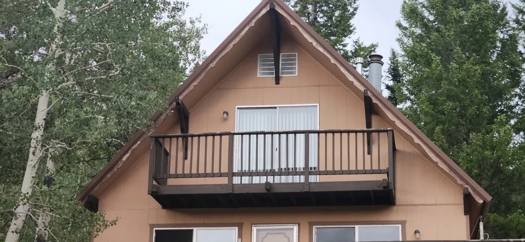 Gable roofline featuring a second-story balcony with wood railing and sliding glass door access