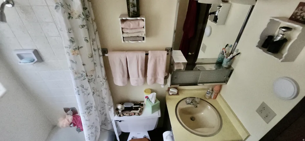 Wall-mounted mirror with overhead light fixture, built-in medicine cabinet, and corner vanity with integrated sink