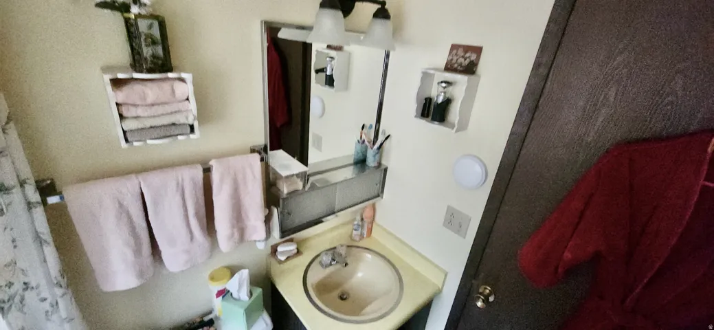 Wall-mounted mirror with overhead light fixture, built-in medicine cabinet, and corner vanity with integrated sink
