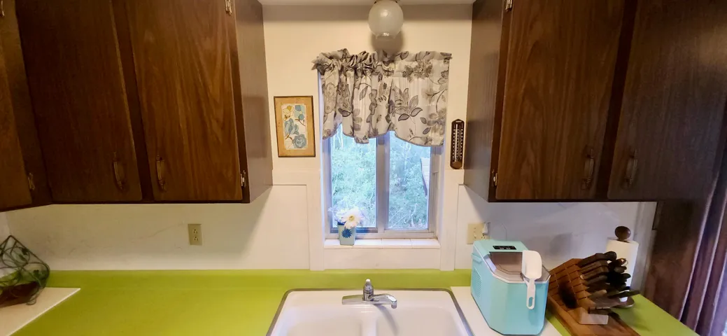 Wood-finish upper cabinetry, a white porcelain sink, and a single-handle chrome faucet