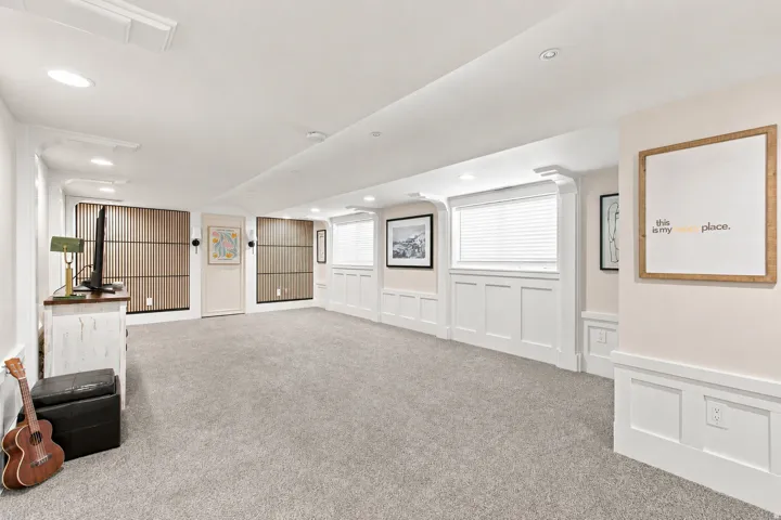 Spacious room featuring light-colored carpeting, recessed lighting, and white wainscoting