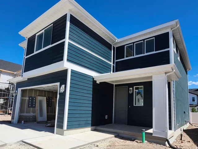 Two-story exterior with multi-toned horizontal siding, white trim, multiple windows, and an attached garage