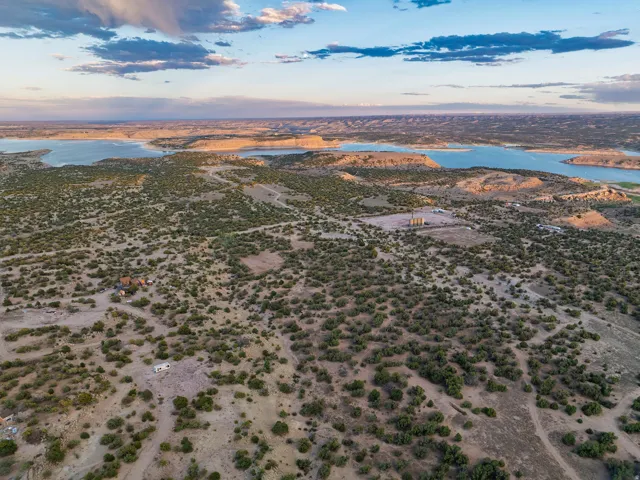 Expansive landscape featuring distant bodies of water, scattered green foliage, and natural terrain
