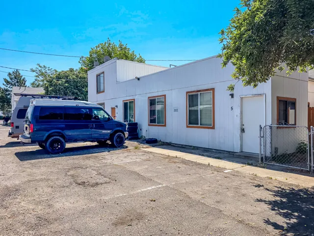 White-paneled exterior with brown-trimmed windows, fenced side yard, and paved parking area