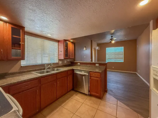 Kitchen featuring wood-finish cabinetry, a stainless steel double basin sink, and integrated stainless steel dishwasher