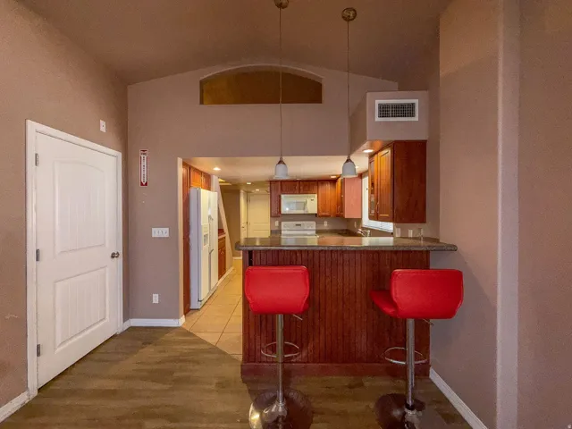 Vaulted ceiling with an arched transom window, wood-finish flooring, and a kitchen island with pendant lighting
