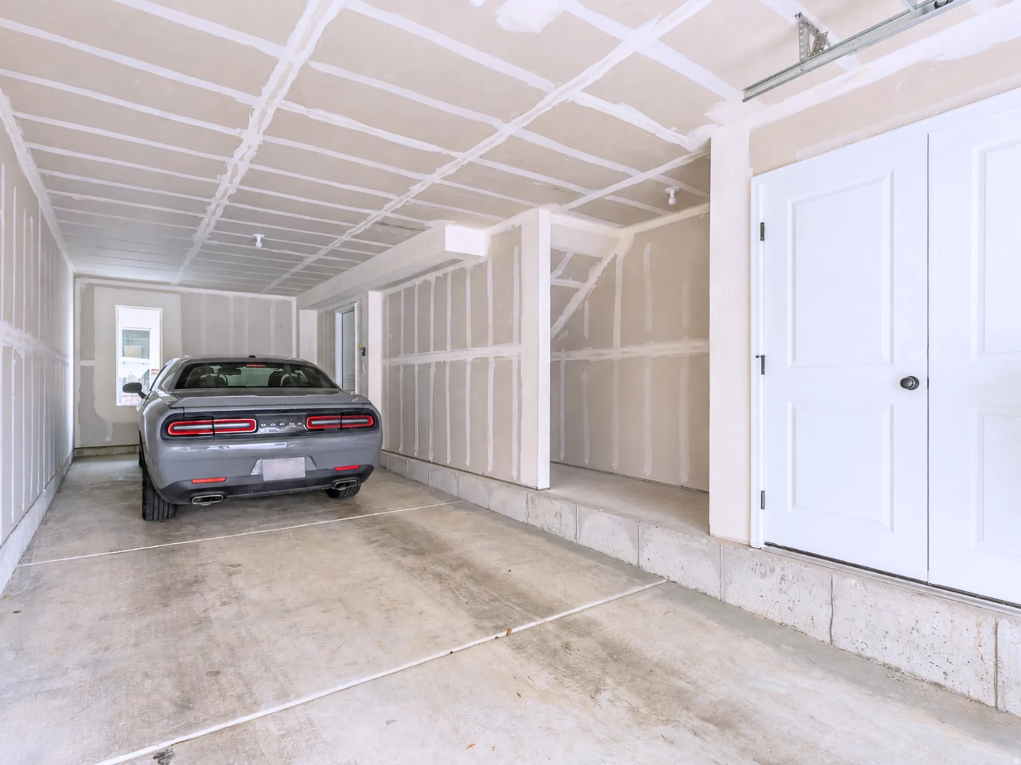 Spacious garage area featuring concrete flooring, unpainted drywall, and a window