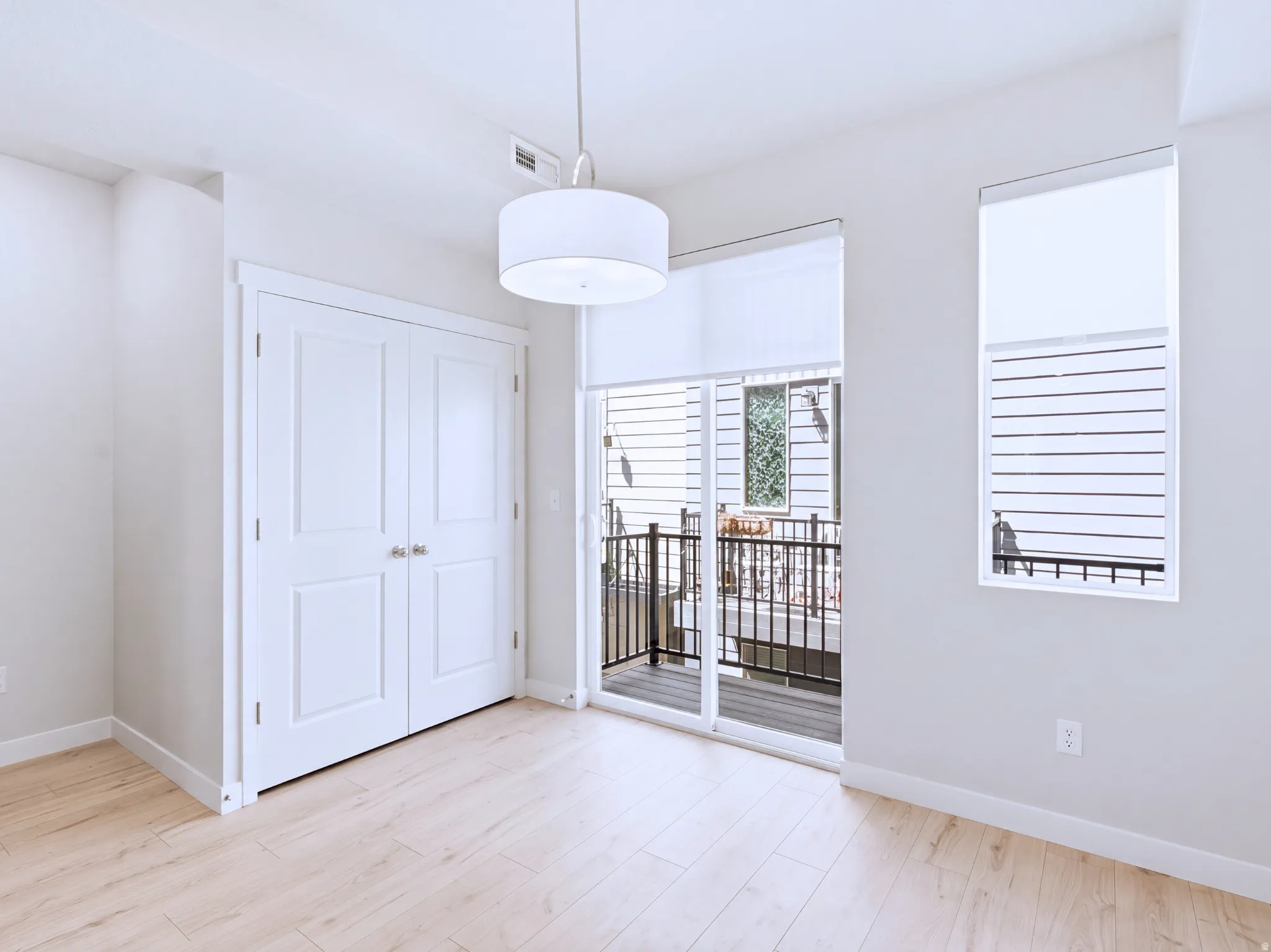 Light wood-finish flooring, white walls, and a large drum pendant light