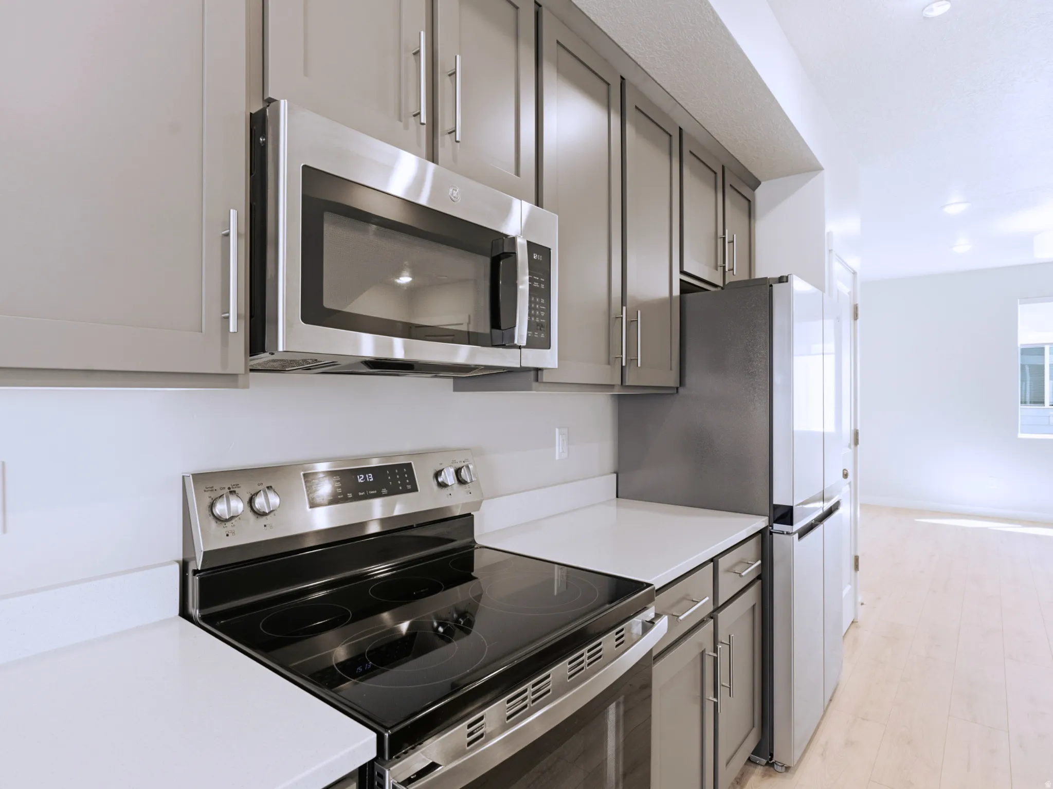 Kitchen featuring gray cabinetry, stainless steel appliances, solid surface countertops, and wood-finish flooring