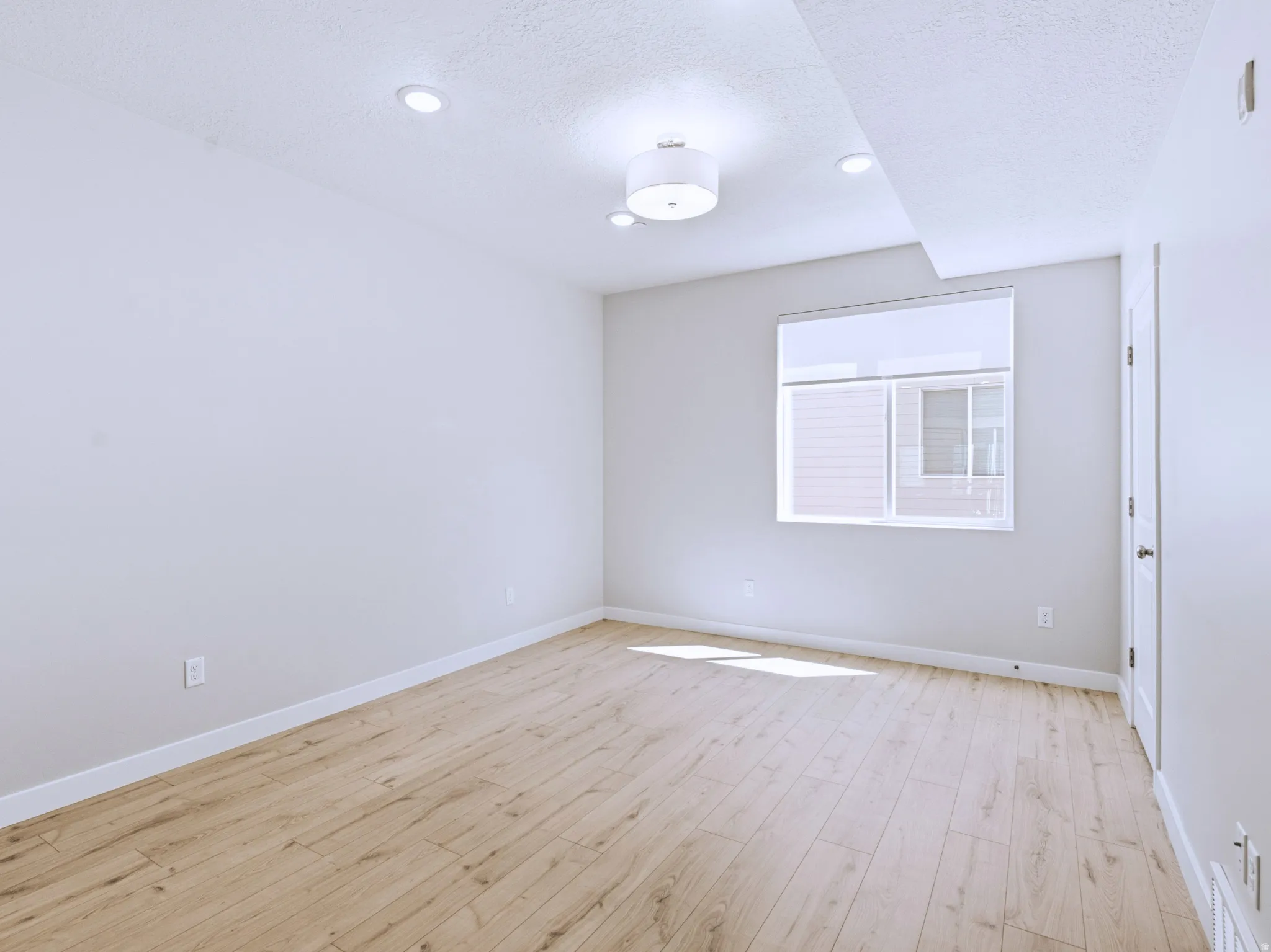 Recessed lighting, wood-finish flooring, white trim, a single window, and a flush-mount ceiling light fixture