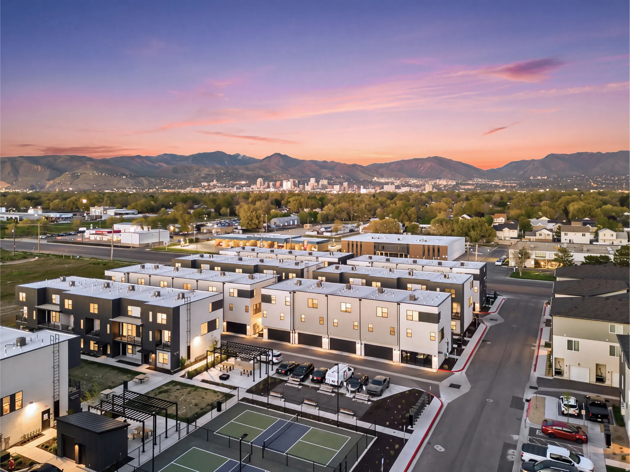 Modern townhome community featuring contemporary exterior designs, mountain backdrop, and multiple recreational courts