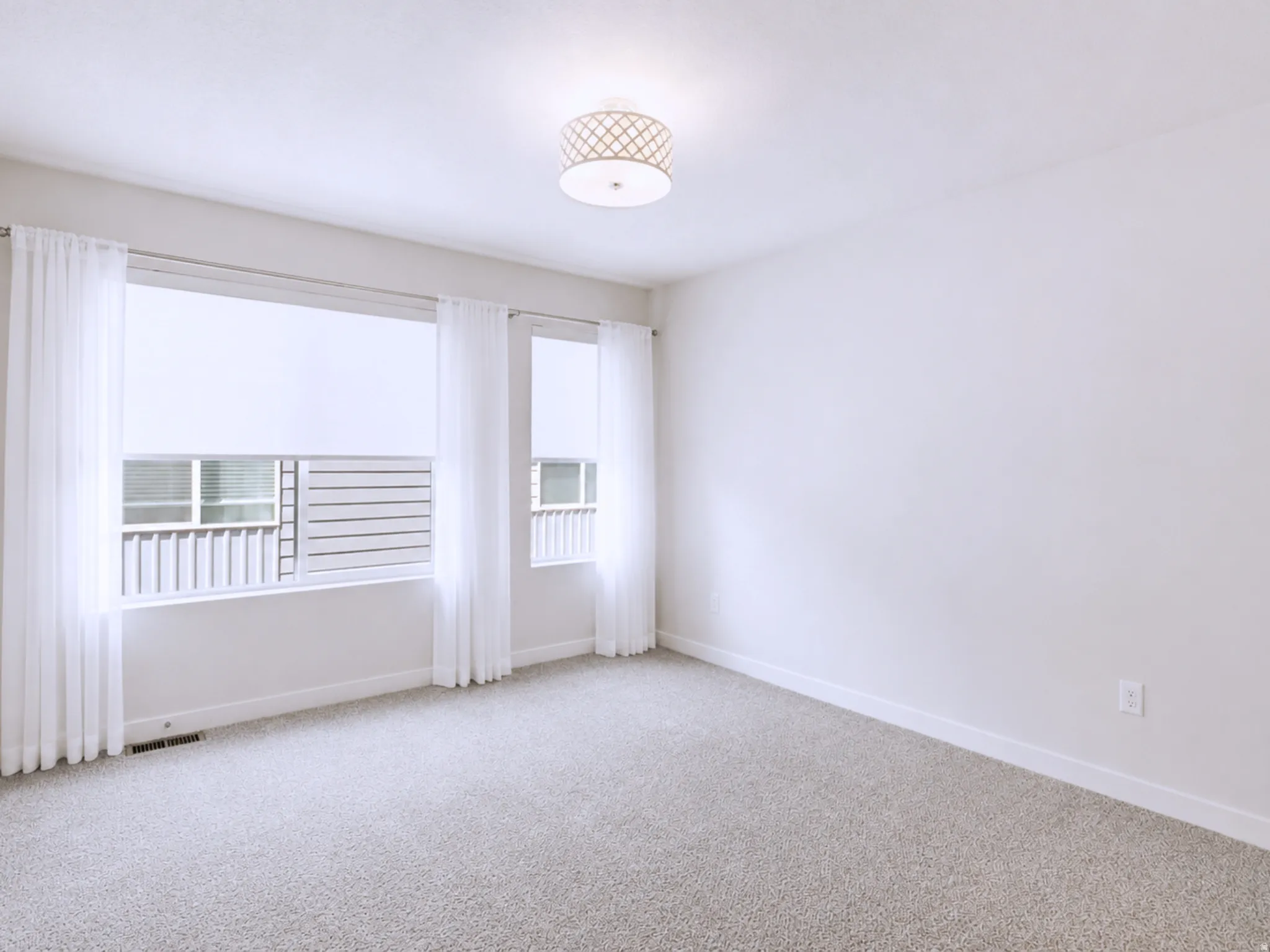 Neutral wall color, wall-to-wall carpeting, decorative semi-flush mount ceiling light, and window treatments