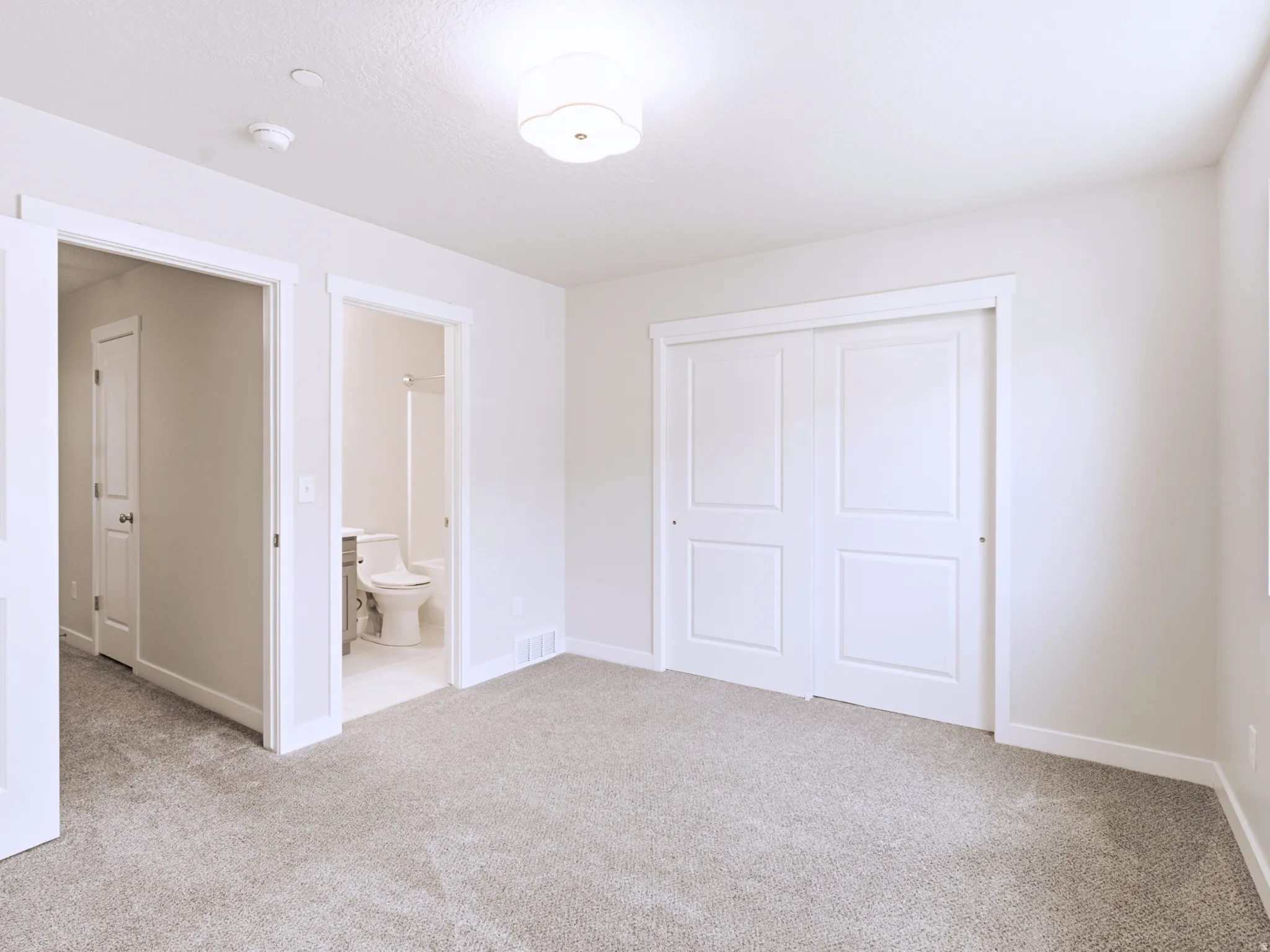 Neutral-toned carpeting, white walls, white trim, recessed lighting, and a white ceiling fixture
