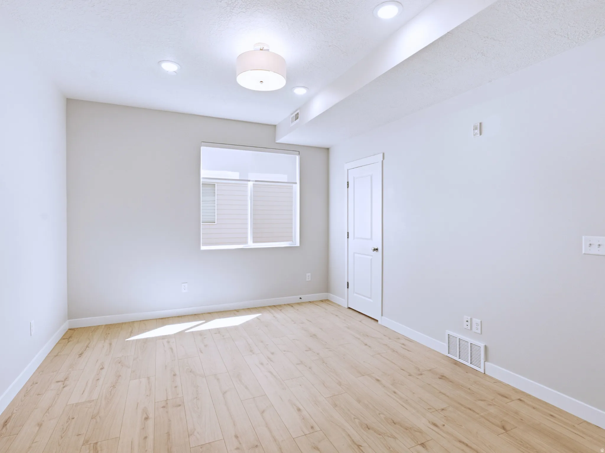 Recessed lighting, drum pendant light fixture, wood-finish flooring, white trim, and a white interior door