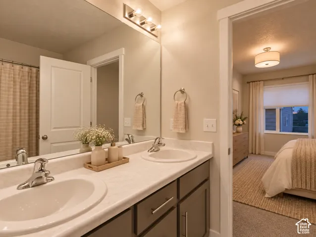Dual-vanity bathroom featuring a light-toned solid surface countertop, undermount sinks, polished chrome hardware, and gray shaker-style cabinetry with a full-width mirror