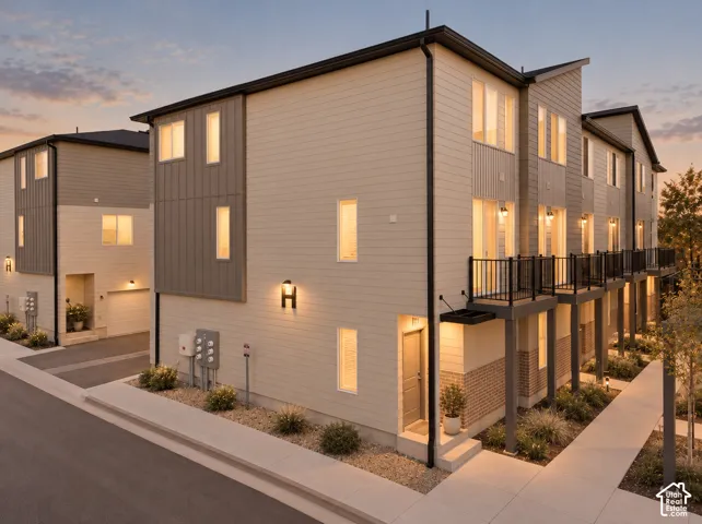Multi-level exterior featuring horizontal and vertical siding, brick accents, second-story balconies with metal railings, and attached garages
