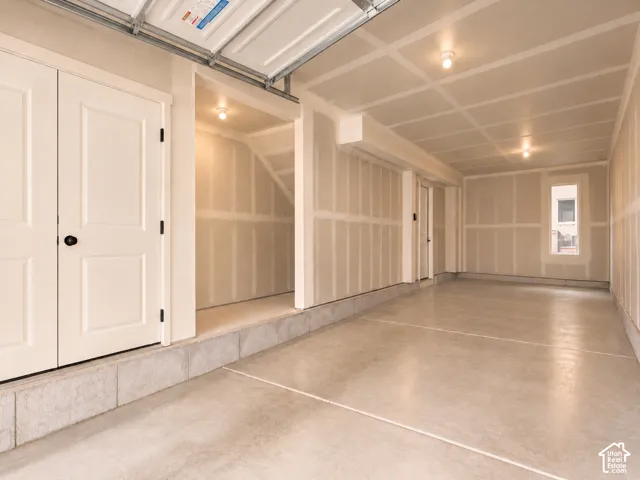 Garage space featuring concrete flooring, finished drywall, recessed ceiling lighting, a dedicated storage alcove, and a window