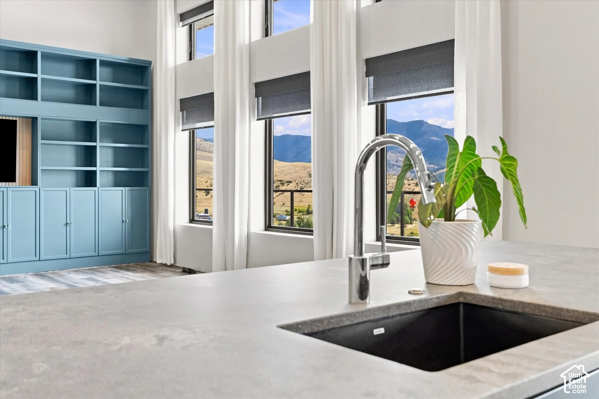 Built-in shelving and cabinetry, high ceilings, large windows, wood-finish flooring, and a contemporary sink with a chrome faucet