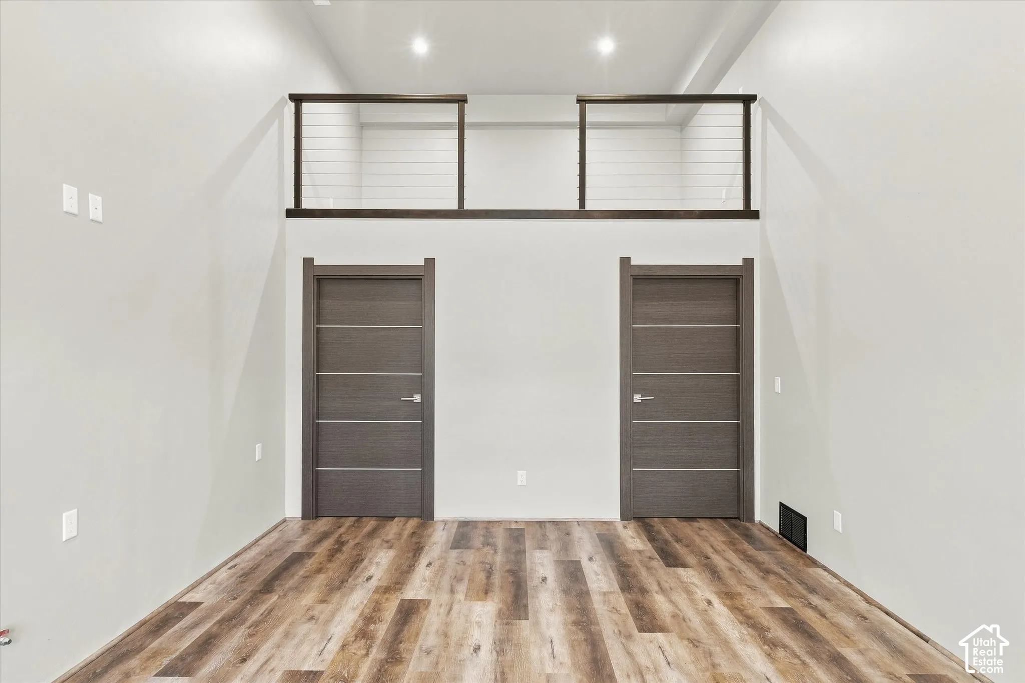 Tall ceilings with recessed lighting, wood-finish flooring, and modern doors with horizontal paneling