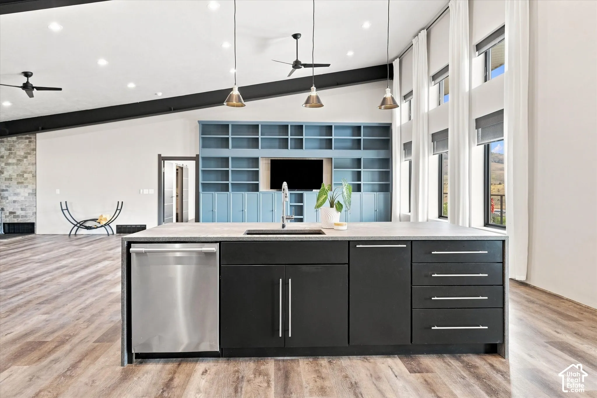 Kitchen island with integrated stainless steel dishwasher, black cabinetry, and a light-colored countertop