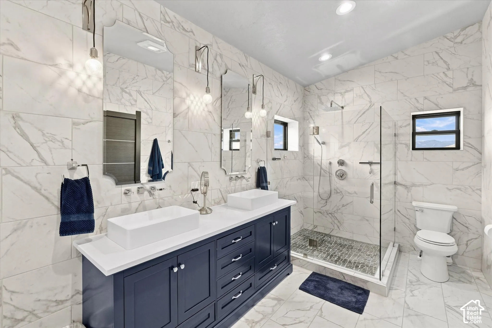 Dual vanity with white rectangular vessel sinks, dark blue cabinetry, and wall-mounted faucets