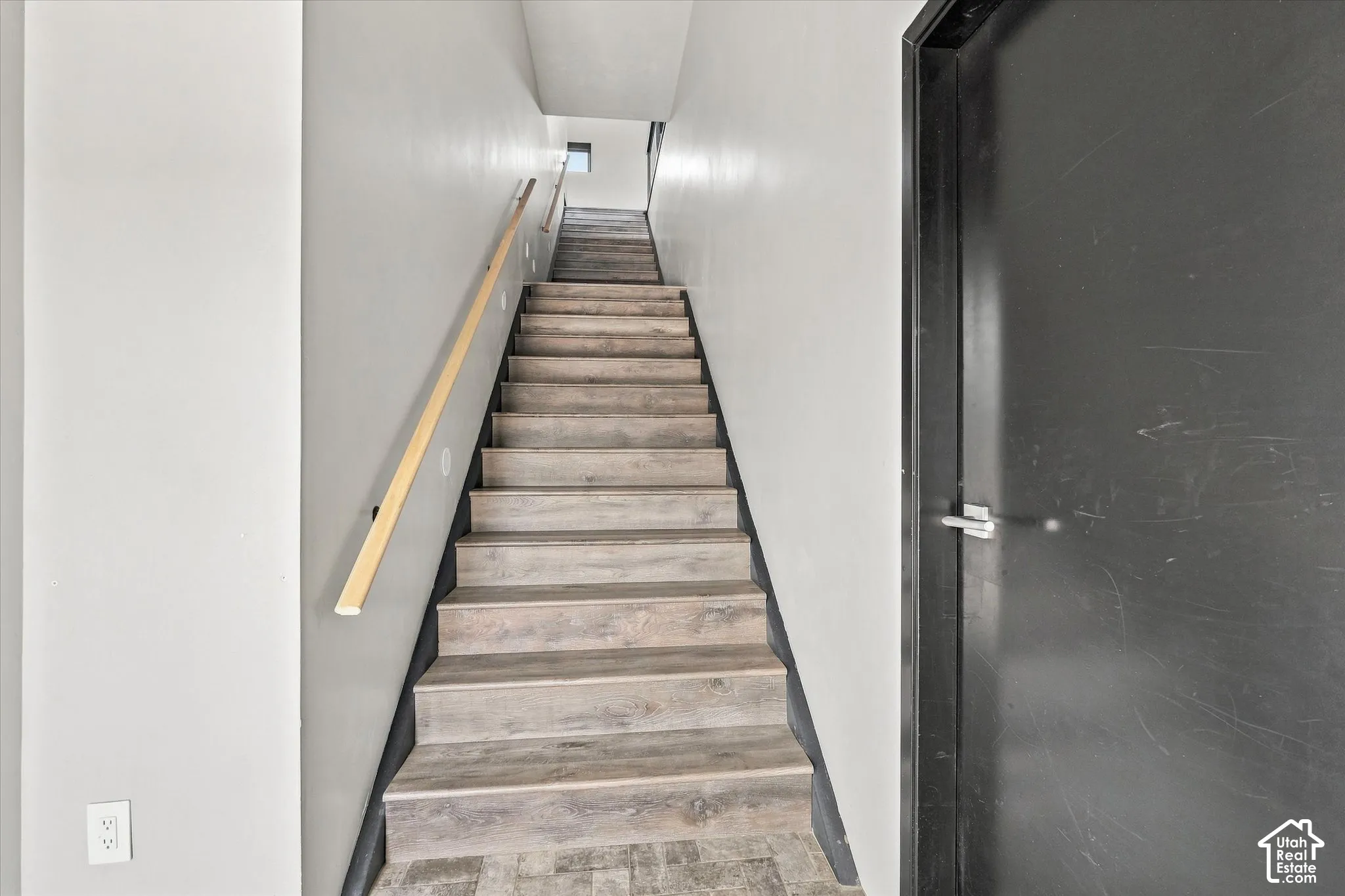 Staircase with wood-finish treads and risers, complemented by a light wood handrail