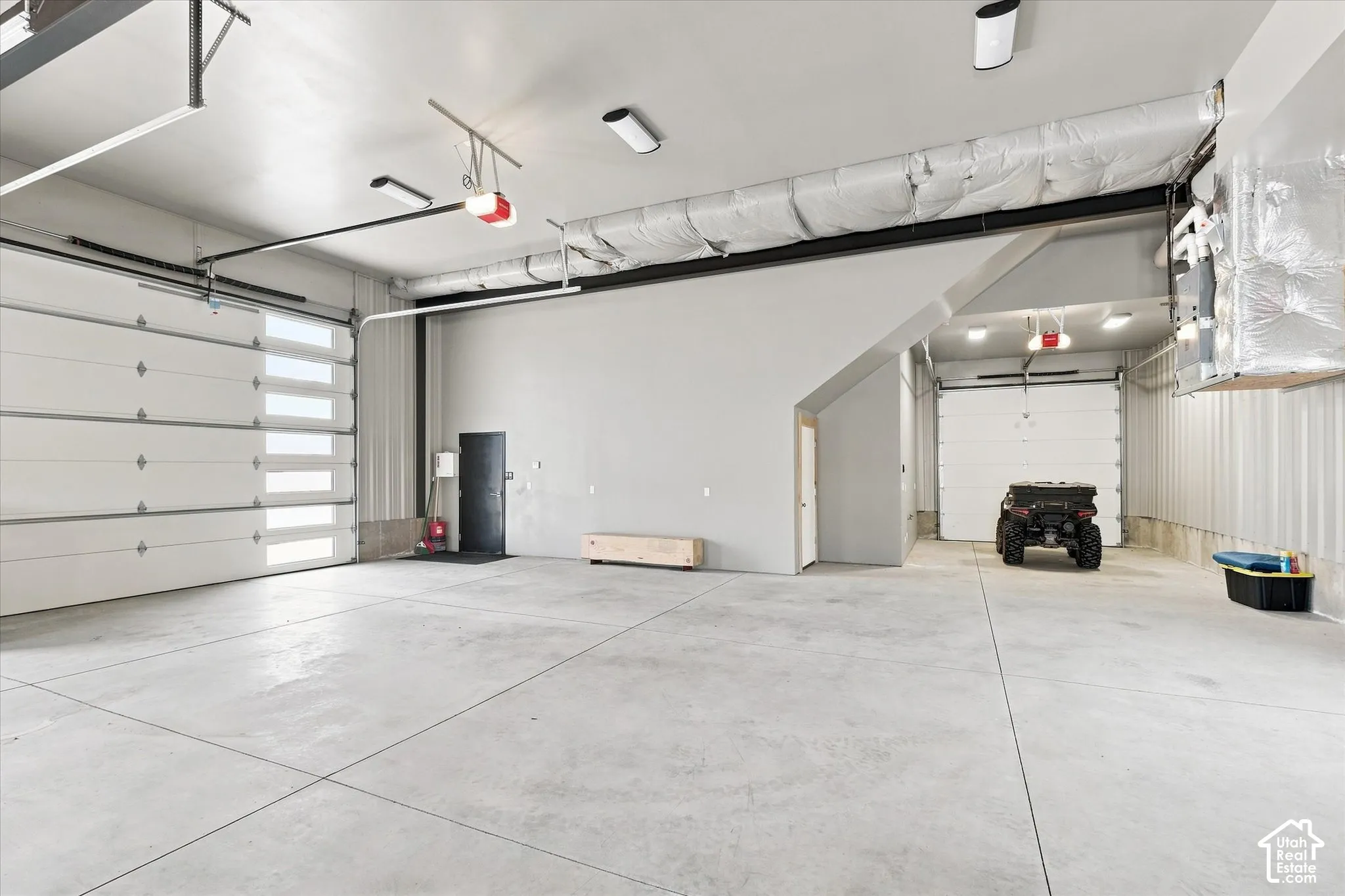 Expansive concrete flooring, multiple overhead garage doors with frosted window panels, and exposed ductwork
