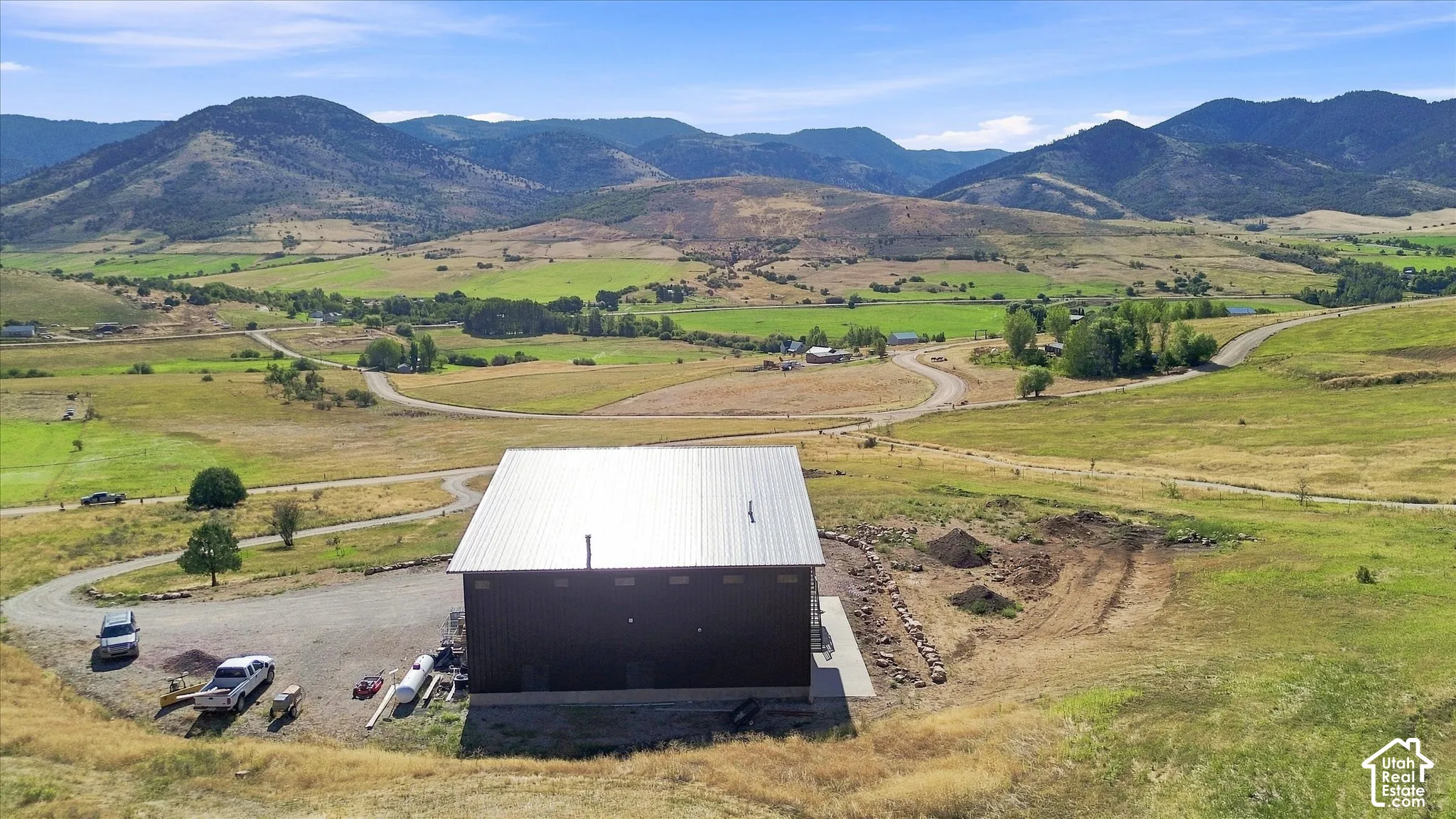 Expansive mountainous backdrop framing a property with a metal roof and dark-toned exterior