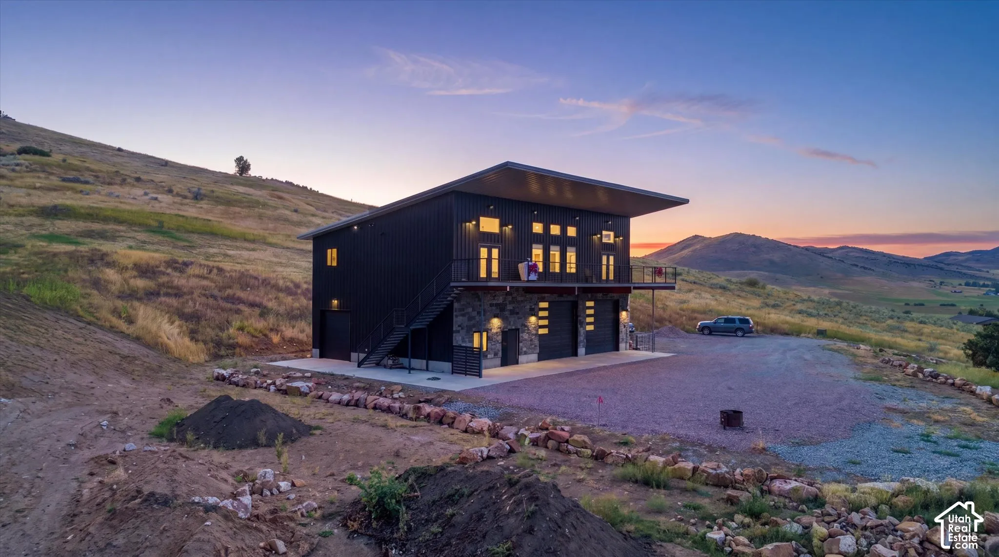Modern architecture with a black corrugated metal exterior, stone facade, and extensive natural surroundings