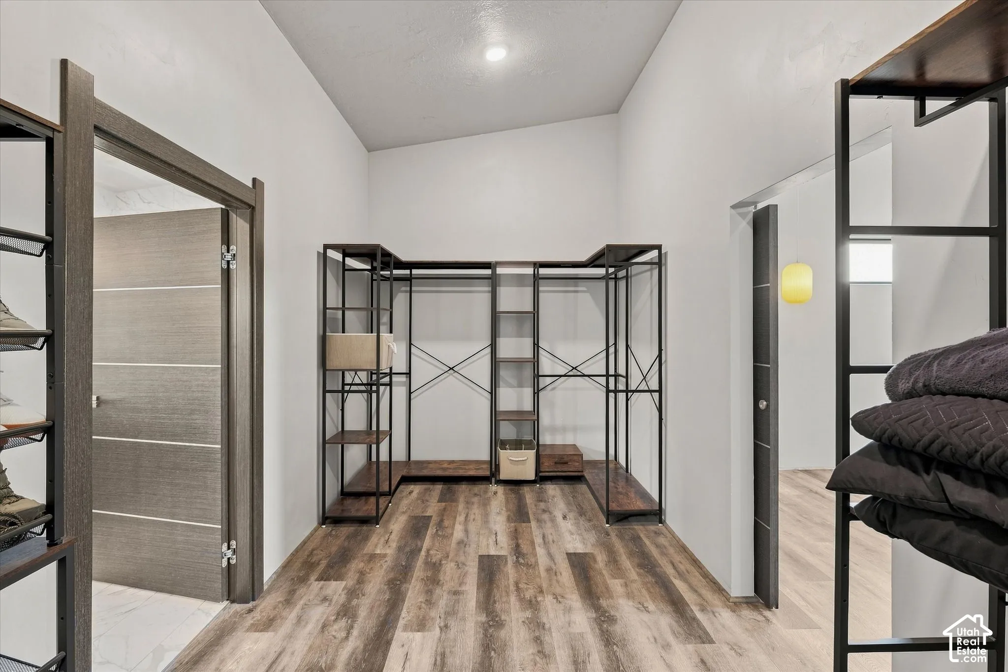 Vaulted ceiling with recessed lighting, wood-finish flooring, and built-in closet shelving
