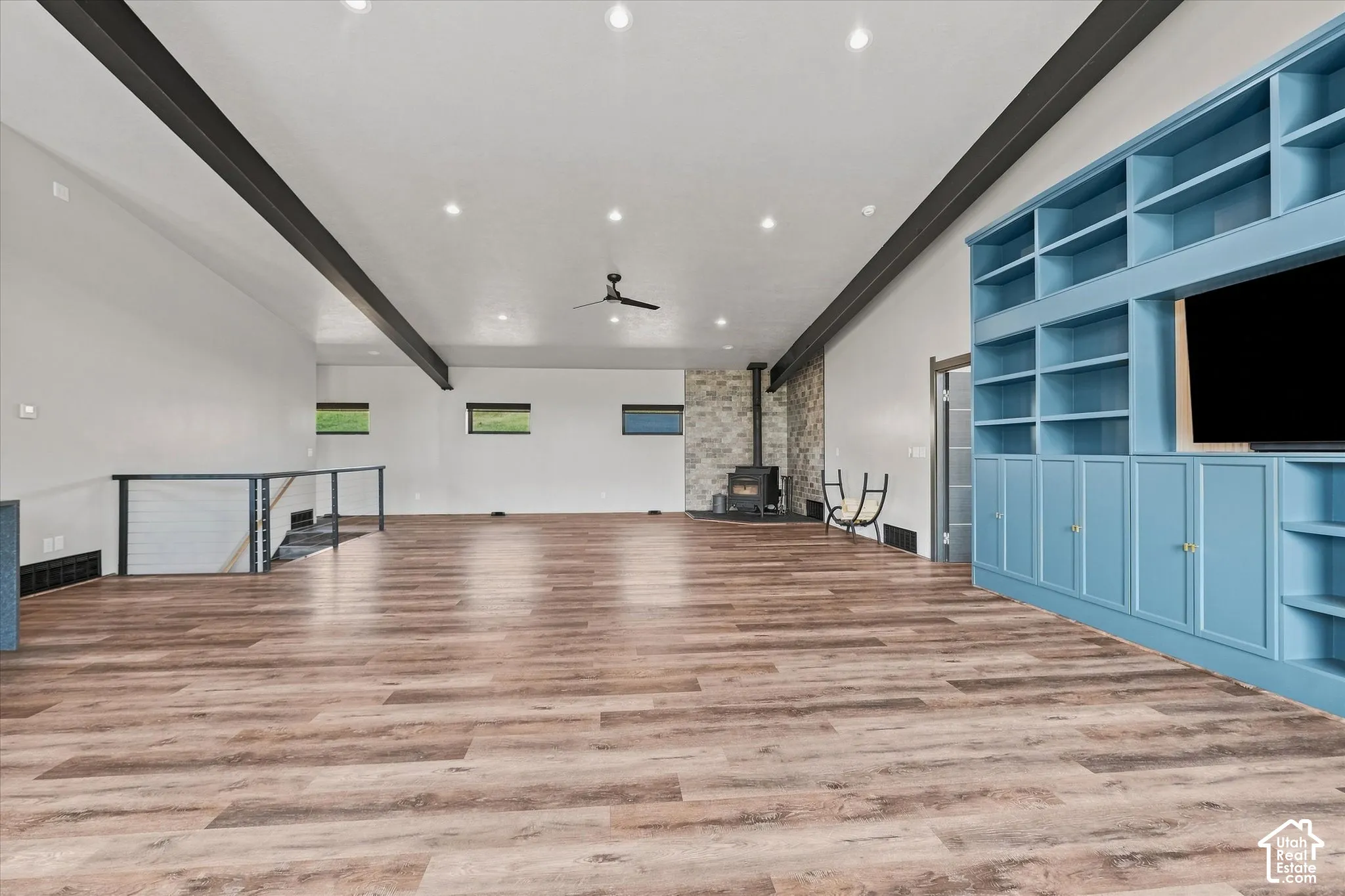 Expansive open-concept loft featuring wood-finish flooring throughout, recessed ceiling lighting, and exposed structural beams