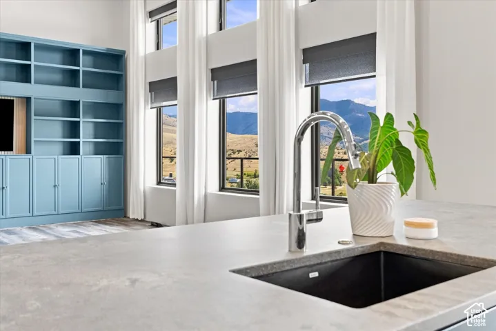 Built-in shelving and cabinetry, high ceilings, large windows, wood-finish flooring, and a contemporary sink with a chrome faucet