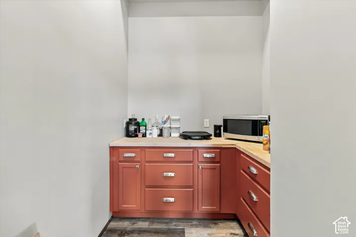 Built-in L-shaped cabinetry with wood-finish countertops, brushed nickel hardware, and wood-finish flooring