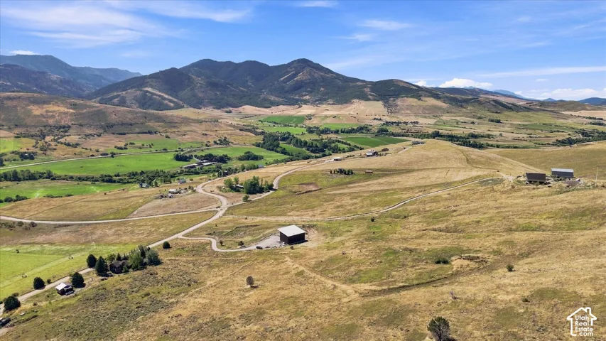 Expansive terrain featuring natural ground cover, established trees, and mountainous topography