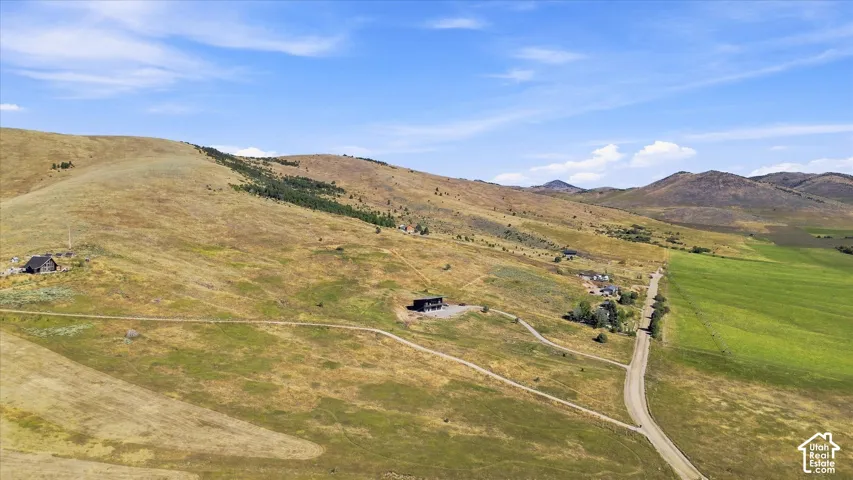 Expansive land featuring a dirt road, multiple structures, and distant mountains