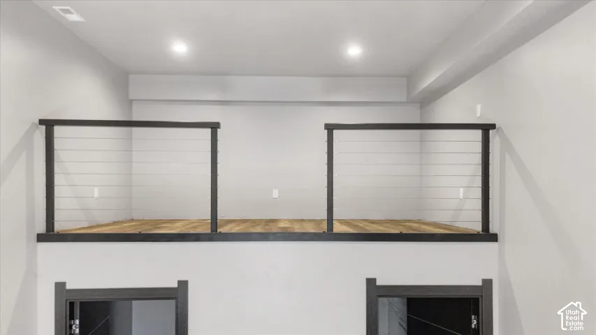 Modern lofted spaces feature black-framed railing systems with horizontal cable design, wood-finish flooring, and recessed ceiling lighting