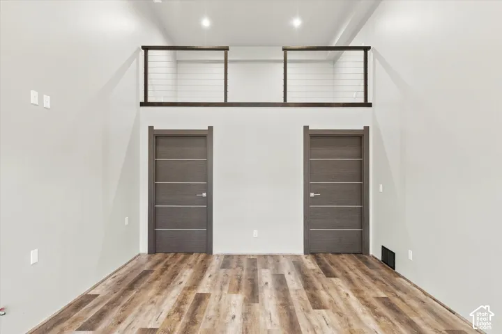 Tall ceilings with recessed lighting, wood-finish flooring, and modern doors with horizontal paneling
