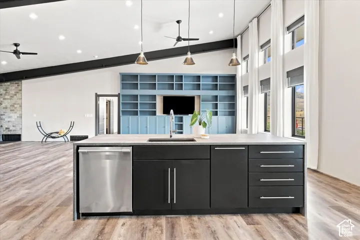 Kitchen island with integrated stainless steel dishwasher, black cabinetry, and a light-colored countertop
