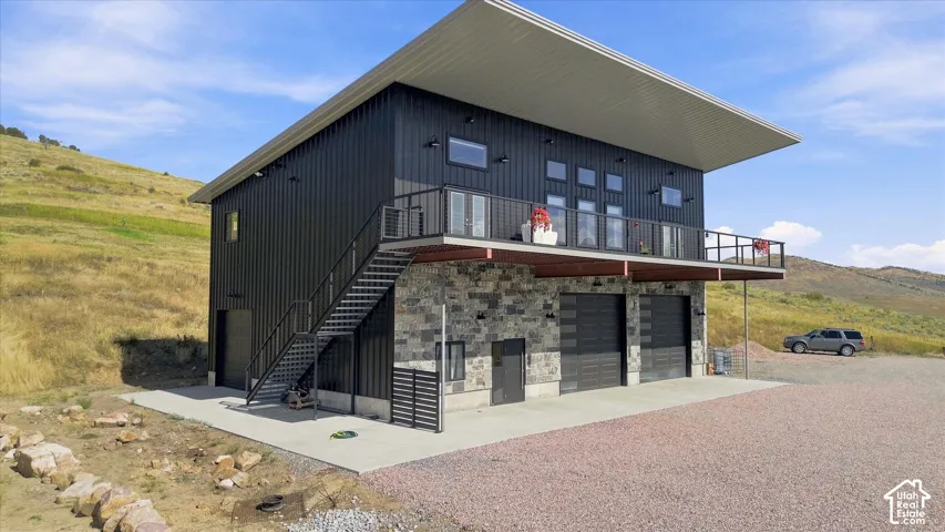 Modern architectural design featuring a striking cantilevered roofline and mixed-material exterior combining corrugated metal cladding with stone base