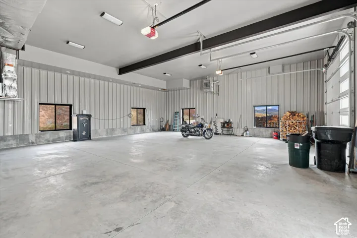 Spacious interior with high ceilings, multiple windows, exposed structural beams, and a large garage door