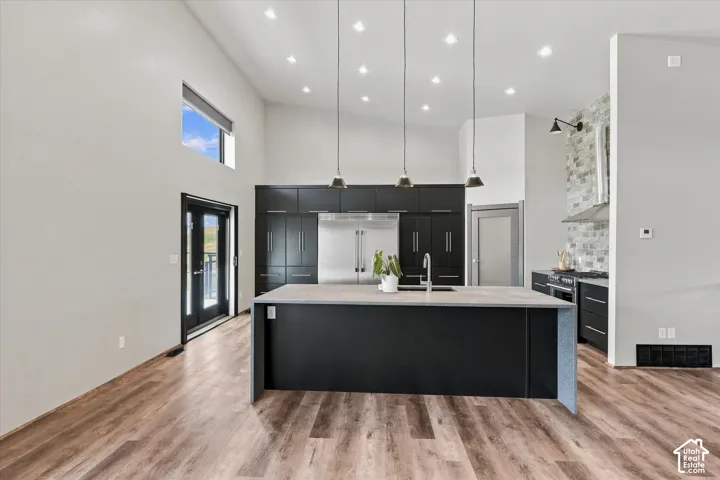 Contemporary kitchen featuring a large waterfall-edge island with black cabinetry, white quartz countertops, and stainless steel appliances