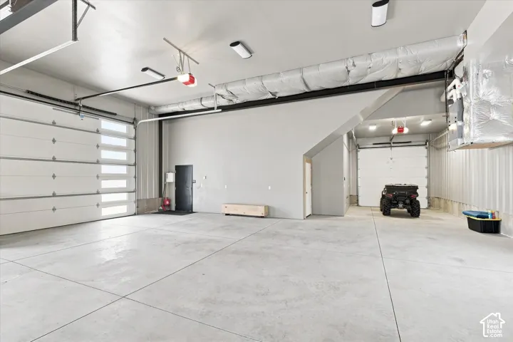 Expansive concrete flooring, multiple overhead garage doors with frosted window panels, and exposed ductwork