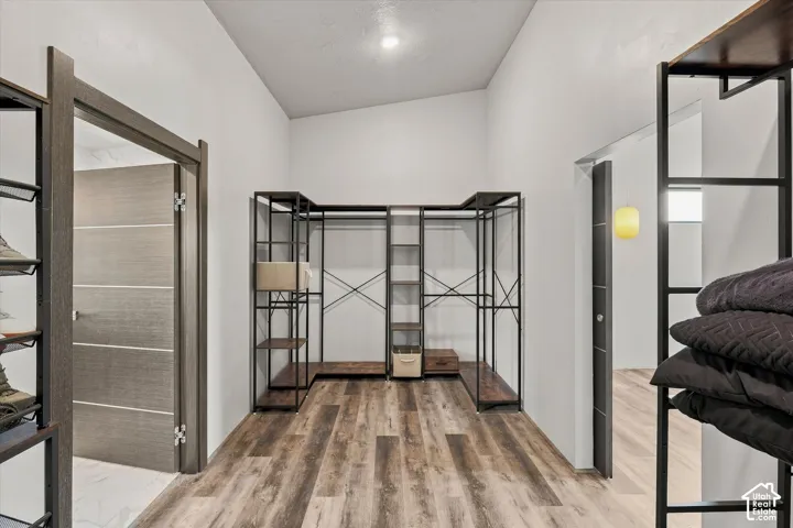 Vaulted ceiling with recessed lighting, wood-finish flooring, and built-in closet shelving